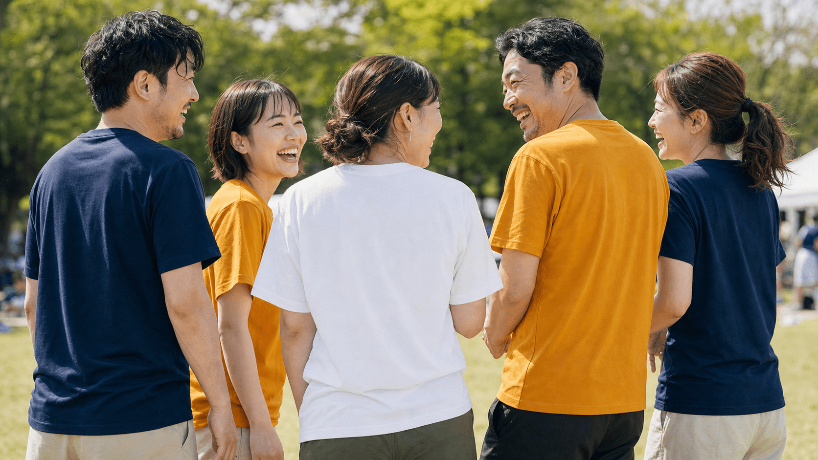 お揃いのTシャツを着た仲間たちが屋外で笑い合っている様子